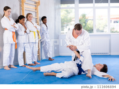 Judo master demonstrating armbar technique in sparring with student Judo master demonstrating armbar technique in sparring with student 111606894