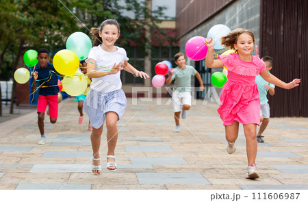 Children with balloons running through city streets Children with balloons running through city streets 111606987