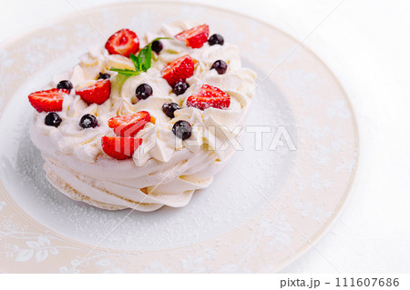 Pavlova cakes with cream and fresh berries on plate 111607686