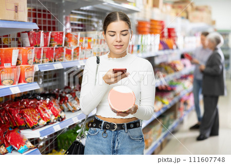Young woman in supermarket scan QR code on instant fast food package Young woman in supermarket scan QR code on instant fast food package 111607748