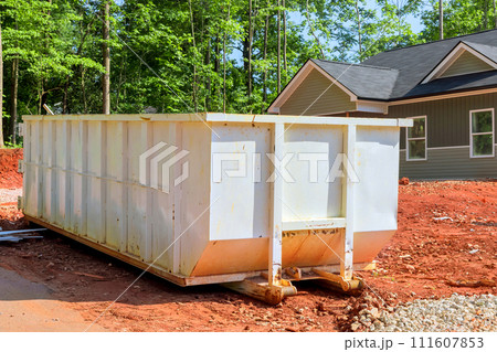 At construction site, there is metal container dumpster for storing repair junk waste 111607853
