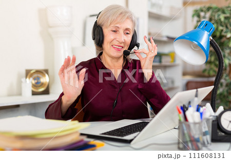 Smiling female operator talking with customer using headset at office 111608131