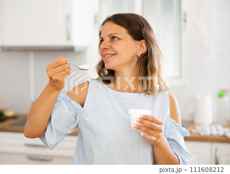 Light breakfast of yogurt and apples for young happy girl in modern kitchen 111608212
