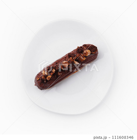 eclair with chocolate and nuts on a white plate 111608346