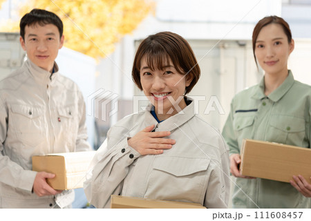 荷物を持つ作業服姿の男女 111608457