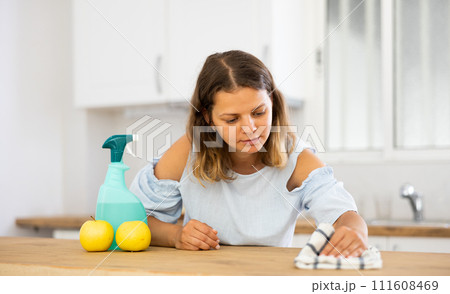 Positive woman cleaning kitchen table at home Positive woman cleaning kitchen table at home 111608469