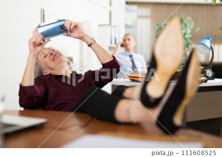 Mature woman office worker using smartphone during break Mature woman office worker using smartphone during break 111608525