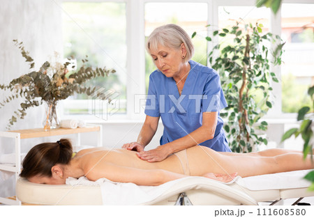 Unrecognizable young woman lies face down and enjoy shoulder massage for body care 111608580