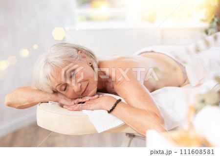 Relaxed mature woman lying with closed eyes on massage bed 111608581