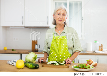 Mature woman cutting fresh vegetables for dinner 111608957