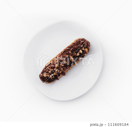 eclair with chocolate and nuts on a white plate 111609184