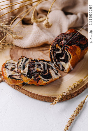 Wooden board with tasty cut poppy seed bun 111609264