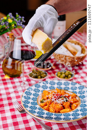 hef grates cheese to the plate with fresh penne pasta hef grates cheese to the plate with fresh penne pasta 111609747