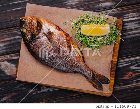 Board with fried dorado on wooden background Board with fried dorado on wooden background 111609773