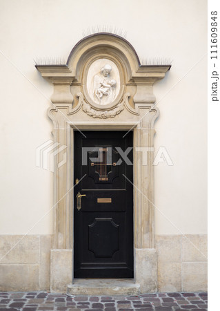 A wooden black door with small window in an arched doorway A wooden black door with small window in an arched doorway 111609848