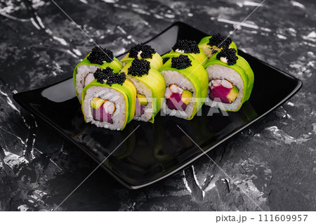 Sushi roll covered with avocado with tuna and black caviar Sushi roll covered with avocado with tuna and black caviar 111609957