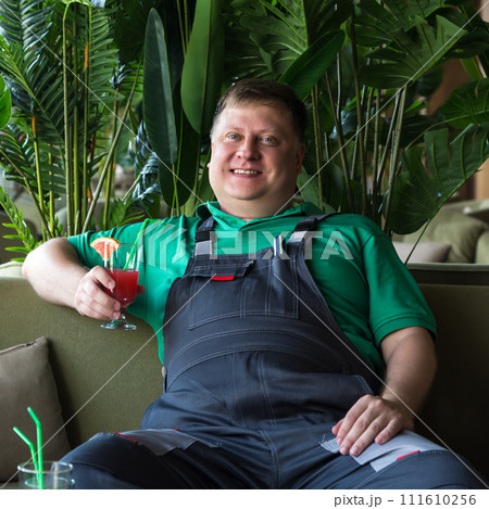 Portrait of an adult man in work clothes drinking a cocktail at lunch while sitting in a cool room Portrait of an adult man in work clothes drinking a cocktail at lunch while sitting in a cool room 111610256
