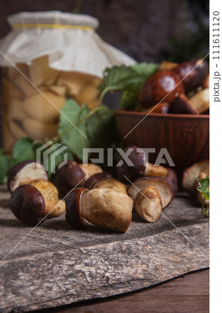 Pile of Imleria Badia or Boletus badius mushrooms commonly known as the bay bolete with canned mushroom in glass jar on vintage wooden background.. Pile of Imleria Badia or Boletus badius mushrooms commonly known as the bay bolete with canned mushroom in glass jar on vintage wooden background.. 111611120