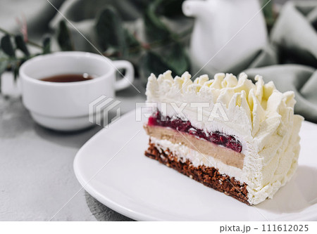 Layered Mousse Cake on white plate and cup of tea Layered Mousse Cake on white plate and cup of tea 111612025