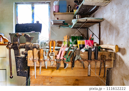 File, screwdriver, hammer, pliers, garden tools on a wooden shelf in a garage 111612222