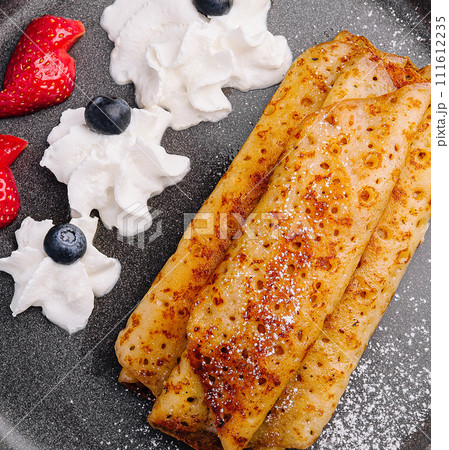 pancakes in a plate with strawberries, whipped cream 111612235