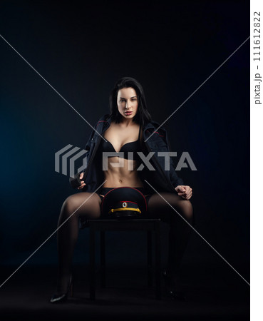 sexy girl in a military police uniform on a dark background with handcuffs and a rubber button, role-playing and striptease for adults 111612822