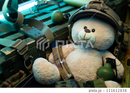 A teddy bear in a military helmet among a pile of military ammunition, a rifle, grenades, a bulletproof vest, a helmet and other tactical airsoft items A teddy bear in a military helmet among a pile of military ammunition, a rifle, grenades, a bulletproof vest, a helmet and other tactical airsoft items 111612838