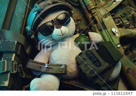 A teddy bear in a military helmet among a pile of military ammunition, a rifle, grenades, a bulletproof vest, a helmet and other tactical airsoft items A teddy bear in a military helmet among a pile of military ammunition, a rifle, grenades, a bulletproof vest, a helmet and other tactical airsoft items 111612847