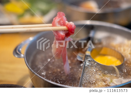 Chopstick holding sliced meat. hot pot with cheese fondue Chopstick holding sliced meat. hot pot with cheese fondue 111613573