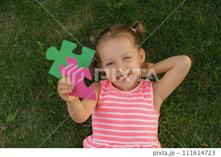 The child holds two pieces of a large puzzle in his hands. Photo on the topic of logical thinking and development The child holds two pieces of a large puzzle in his hands. Photo on the topic of logical thinking and development 111614723