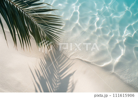 Water and sand surface with tropical palm leaves shadow. Green palm leaf shadow on white sand beach of an ocean shore. Tropical background for summer vacation at the beach. Calm sea, perfect vacation 111615906