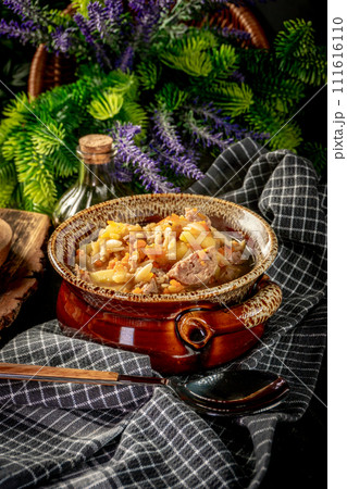 Pea soup with pieces of white sausage, potatoes and small dumplings. 111616110