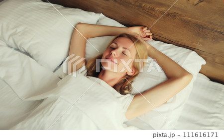 Young woman sleeping lying in bed on white soft comfortable pillow in bedroom at home Young woman sleeping lying in bed on white soft comfortable pillow in bedroom at home 111616171