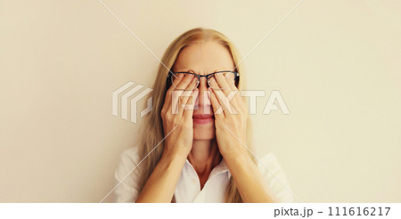 Tired overworked woman employee rubbing her eyes suffering from eye strain, dry eye syndrome Tired overworked woman employee rubbing her eyes suffering from eye strain, dry eye syndrome 111616217