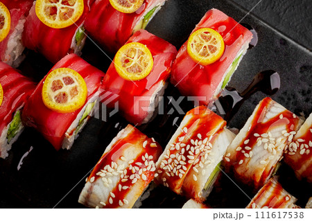 Vibrant sushi rolls with tuna, eel, kumquat and sesame on dark slate Vibrant sushi rolls with tuna, eel, kumquat and sesame on dark slate 111617538