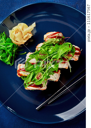 Gourmet sushi roll with salmon and greens on blue plate 111617567