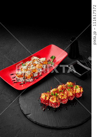 Gourmet sushi rolls on red and black dishware 111617572