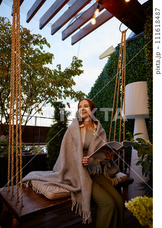 Young woman wrapped in warm blanket in cozy place 111618487