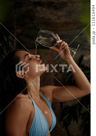 Hot sensual woman pouring water on face from glass Hot sensual woman pouring water on face from glass 111618494