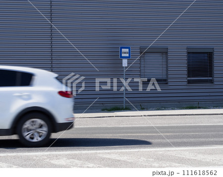 Bus stop and road with a white car in motion 111618562