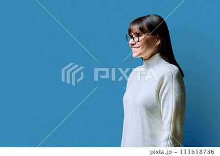 Profile view of middle aged happy woman, blue background, copy space Profile view of middle aged happy woman, blue background, copy space 111618736