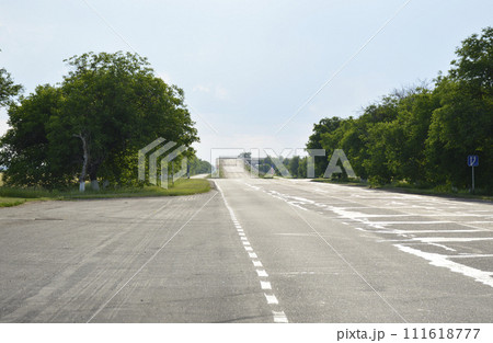 The asphalt road goes into the distance and ends with an ascent to a bridge 111618777