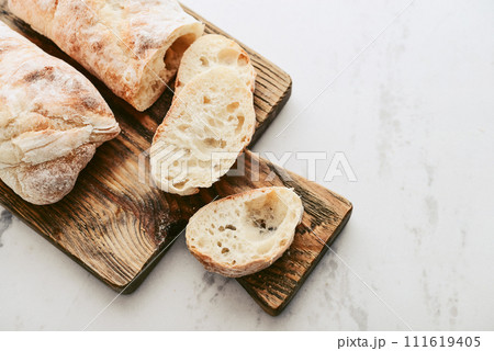 Rustic French sourdough baguettes on wooden cutting board 111619405