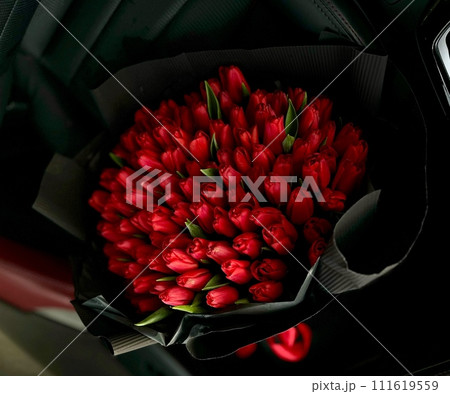 A large bouquet of bright red tulips on a red car A large bouquet of bright red tulips on a red car 111619559