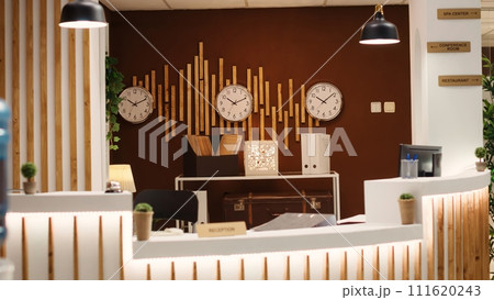Warm hospitality industry hotel lobby check in front desk awaiting travelling visitors. Empty cozy resort in stylish hotel lounge interior reception counter ready to welcome guests 111620243