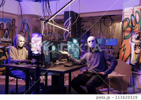 Anonymous scammers recording fraud video while planning phishing attack. Criminals doing online scam while live streaming malicious activity and threatening victim on mobile phone 111620329