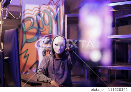 Anonymous man pointing at mobile phone camera while recording ransom video. Criminal streaming threat on smartphone while breaking law and doing illegal activity in abandoned warehouse Anonymous man pointing at mobile phone camera while recording ransom video. Criminal streaming threat on smartphone while breaking law and doing illegal activity in abandoned warehouse 111620342