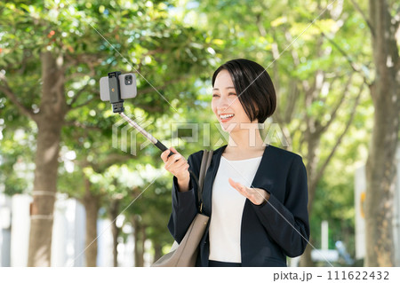 スマホで自撮りをするスーツの女性 スマホで自撮りをするスーツの女性 111622432
