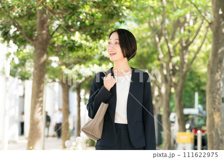 新緑の中で微笑むスーツを着た30代女性 111622975