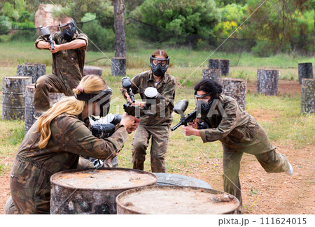 Two active opposing teams with guns playing paintball Two active opposing teams with guns playing paintball 111624015